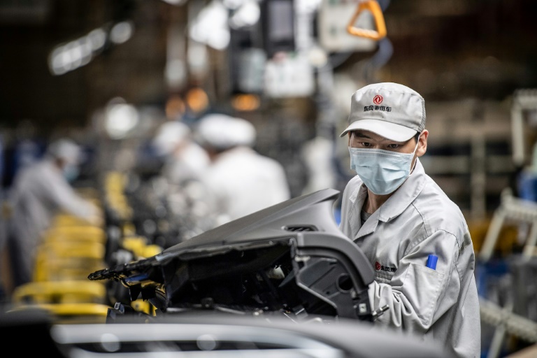 Un empleado con mascarilla trabaja en la cadena de montaje de una fábrica de automóviles, el 23 de marzo de 2020 en la ciudad china de Wuhan.
