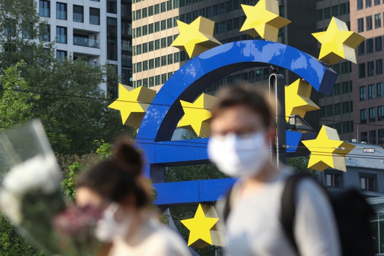 Dos personas con mascarillas faciales pasan frente a un gran símbolo del euro situado junto a la sede de Banco Central Europeo, el 24 de abril de 2020 en la ciudad alemana de Fráncfort