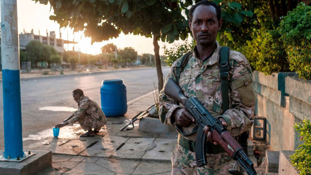 A member of the Amhara Special Forces holds his gun while another washes his face in Humera, Ethiopia, on November 22, 2020. - Prime Minister Abiy Ahmed, last year's Nobel Peace Prize winner, announced military operations in Tigray on November 4, 2020, saying they came in response to attacks on federal army camps by the party, the Tigray People's Liberation Front (TPLF). 
Hundreds have died in nearly three weeks of hostilities that analysts worry could draw in the broader Horn of Africa region, though Abiy has kept a lid on the details, cutting phone and internet connections in Tigray and restricting reporting. (Photo by EDUARDO SOTERAS / AFP) (Photo by EDUARDO SOTERAS/AFP via Getty Images)