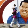 A man carrying a child walks past a mural of Venezuela's President Hugo Chavez in Caracas June 29, 2012. Chavez has a strong lead in most opinion polls as he seeks to beat opposition challenger Henrique Capriles and win a new six-year term in an October 7 election. REUTERS/Carlos Garcia Rawlins (VENEZUELA - Tags: POLITICS ELECTIONS)