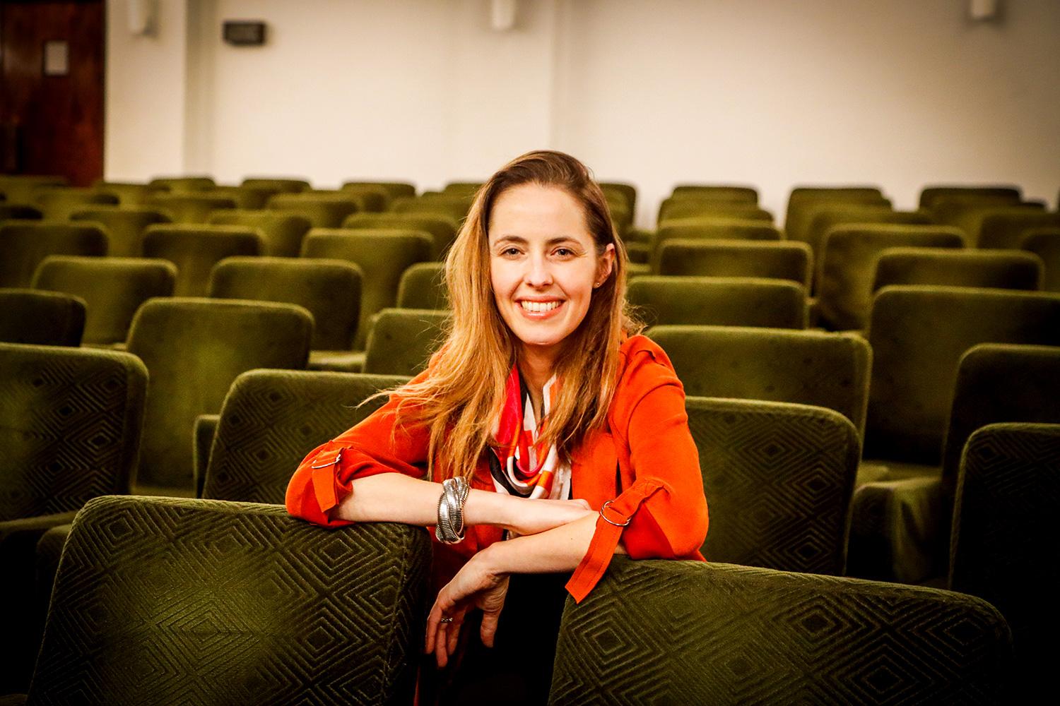 En la imagen aparece la nueva directora del Centro de Extensión CEAC, Dominique Thomann, sentada en las butacas del Teatro Universidad de Chile.