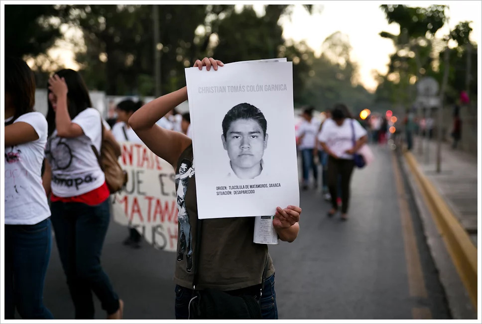 Persona sujetando cartel con rostro de uno de los desaparecidos en una concentración ©Montecruzfoto