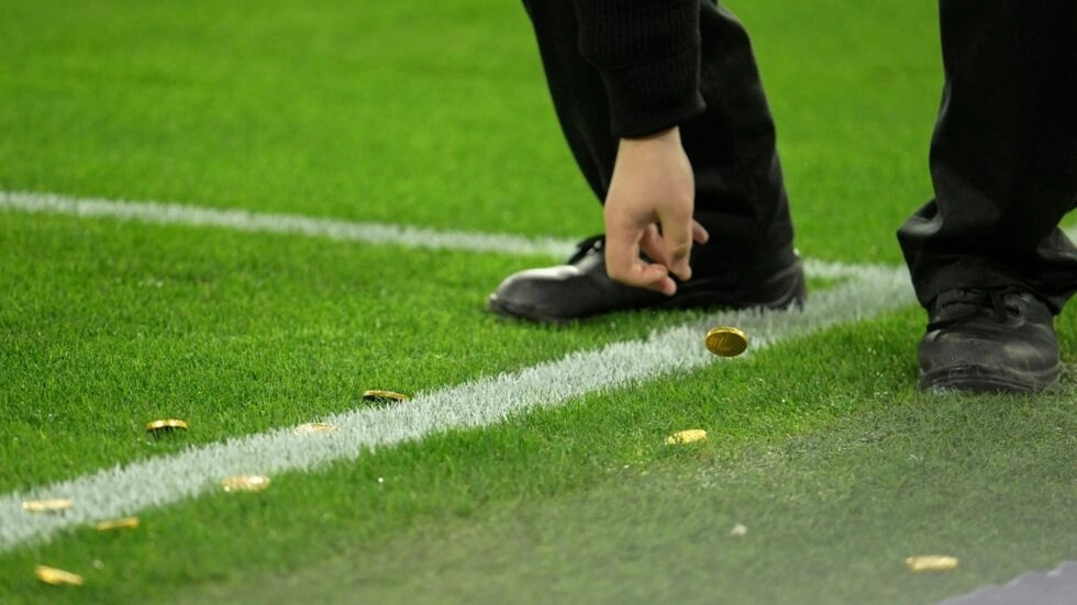 Un miembro del personal recoge las monedas de chocolate lanzadas al campo por los aficionados que protestan contra la DFL durante el partido de fútbol entre el BVB Borussia Dortmund y el SC Freiburg en Dortmund, el 9 de febrero de 2024.
