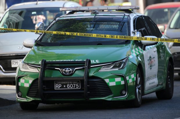 Auto de Carabineros atrás de cintas policiales amarillas