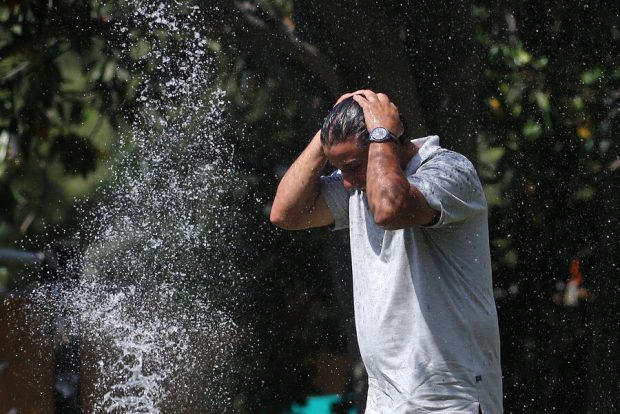 Hombre se refresca durante ola de calor