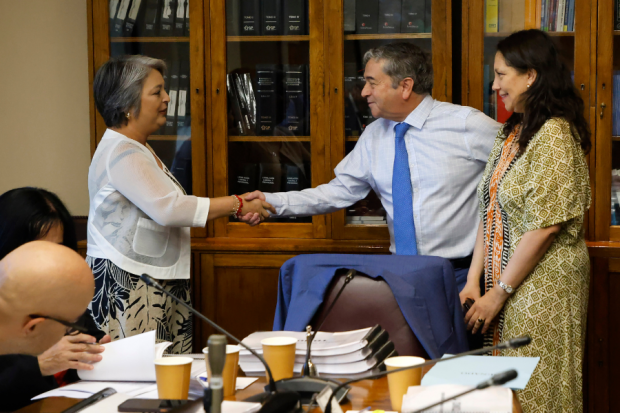 Ministra Jeannette Jara y senador UDI Juan Antonio Coloma, se saludan con un apretón de manos.