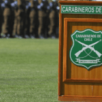 "Equivocadas" e "injustas": bancada de RN oficia al INDH por declaraciones de Ljubetic contra Ley Nain-Retamal Podio de madera con el escudo de Carabineros de Chile. Al fondo se observa una formación de uniformados en una explanada de césped.