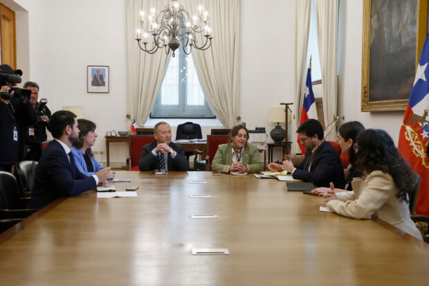 Autoridades de la Segpres y dirigentes del Frente Amplio (FA) sentados alrededor de una mesa de madera en una reunión de coordinación política.