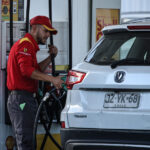 Un trabajador de la Shell se ve sosteniendo la manguera de combustible mientras carga bencina a un vehículo.