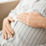 Chile registra la tasa de fecundidad más baja de su historia: por primera vez cae por debajo de un hijo por mujer Plano detalle de una mujer embaraza con las manos sobre su estómago.