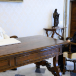 Papa León XIV y Marco Rubio, conversan sentados frente a frente y separados por una mesa de madera.
