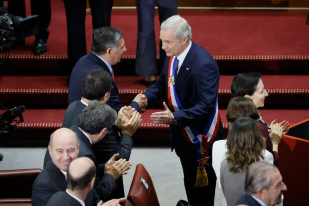 El Presidente Kast sonríe y estrecha la mano de Claudio Alvarado en el Congreso Nacional mientras los asistentes a su primera Cuenta Pública aplauden.