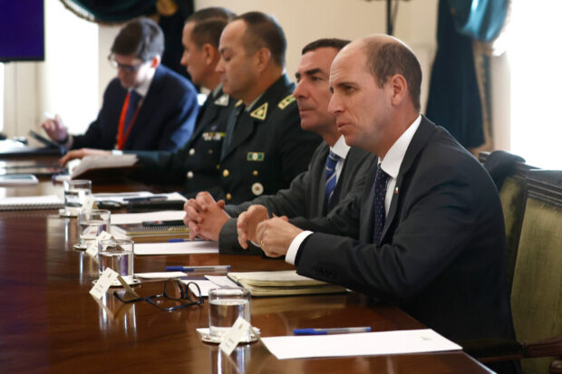 Martín Arrau sentado en una mesa de madera brillante junto al ministro Rabat y autoridades de Gendarmería.